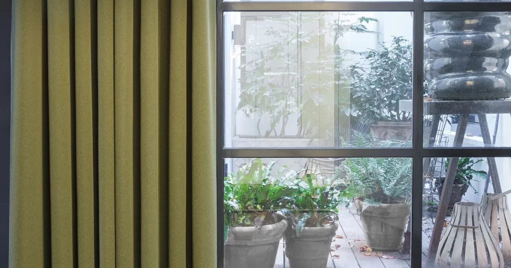 gallery A window with vertical, olive-green curtains.