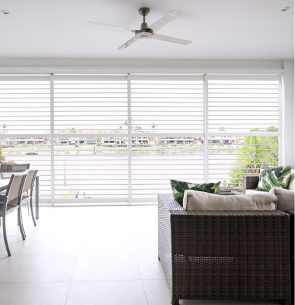 Gallery Bright room with large horizontal blinds, dining table, wicker sofa, ceiling fan, waterfront view.