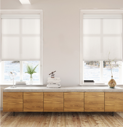 Gallery Wooden sideboard with marble top under two windows with white roller shades and decorative items.
