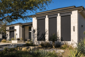 Exterior solar screens shading tall windows on a modern home under strong Texas sun
