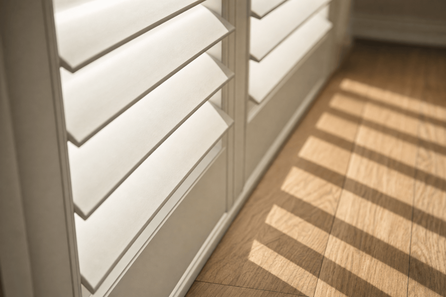 Angled plantation shutter louvers filtering afternoon light across a wood floor