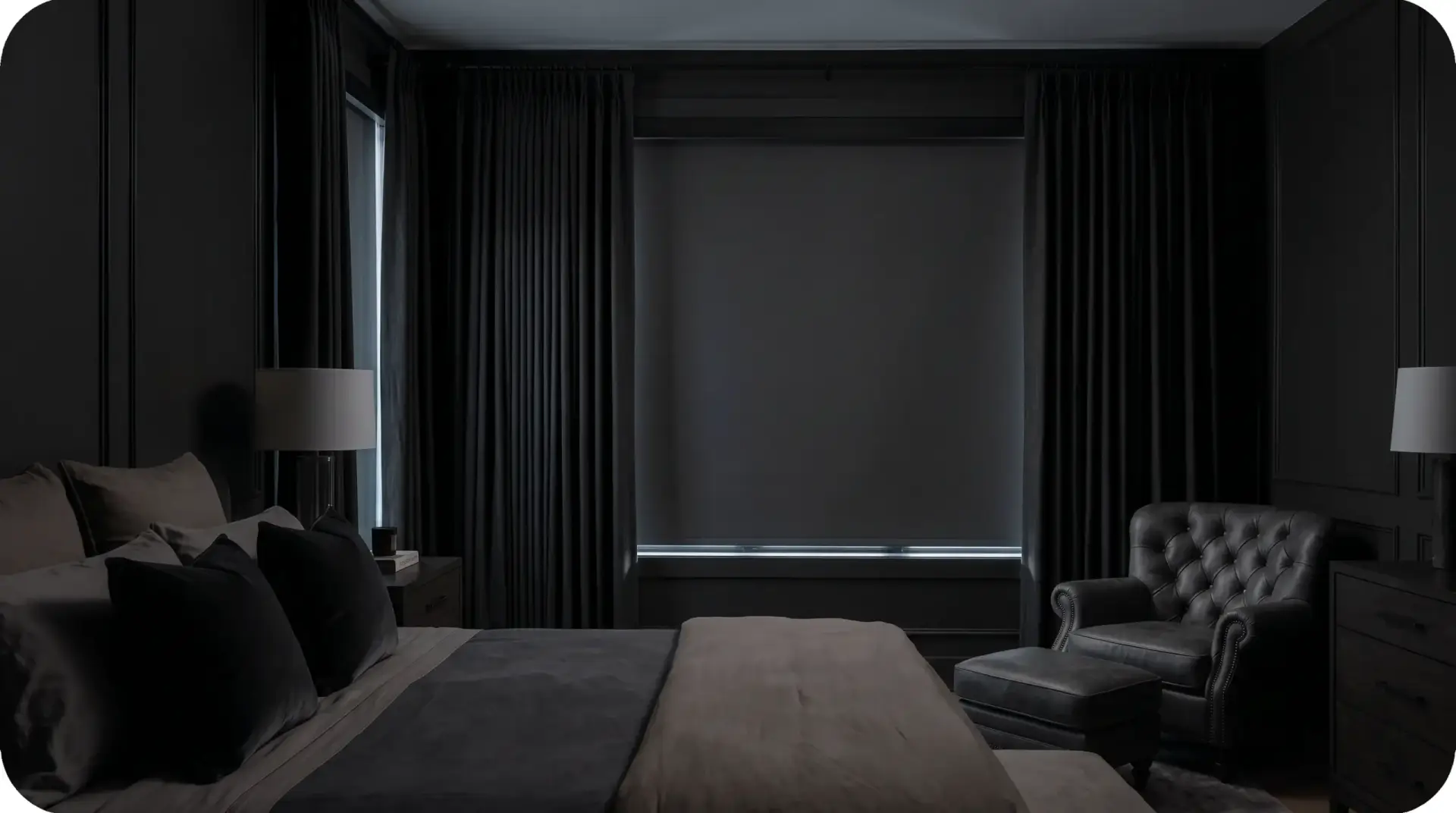 A calm, dark bedroom with a blackout roller shade and drapery keeping the room shaded against bright morning light outside