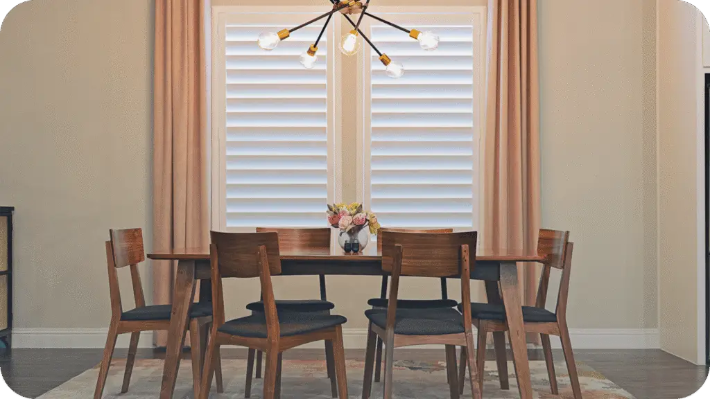 A Dallas dining room dressed with white plantation shutters and floor-length drapery
