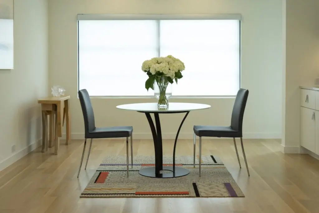 Two light-filtering Colourvue roller shades installed above a modern dining area