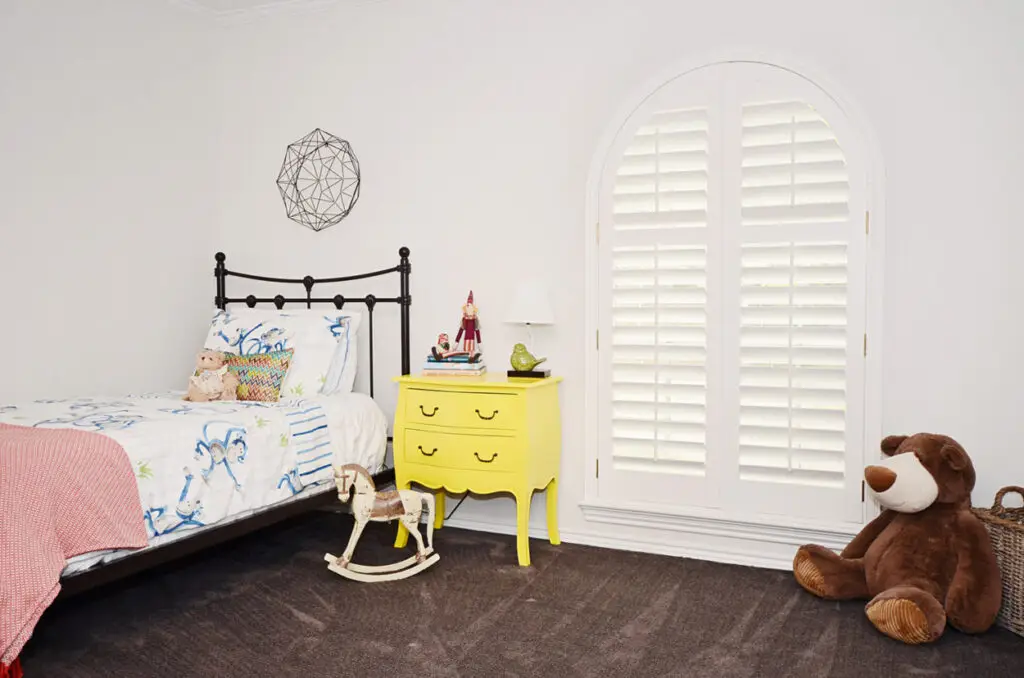 White Highprofile plantation shutters custom-fitted to an arched bedroom opening