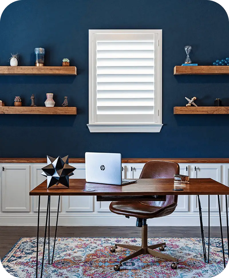 White hardwood painted shutter installed over an office window against a deep blue wall