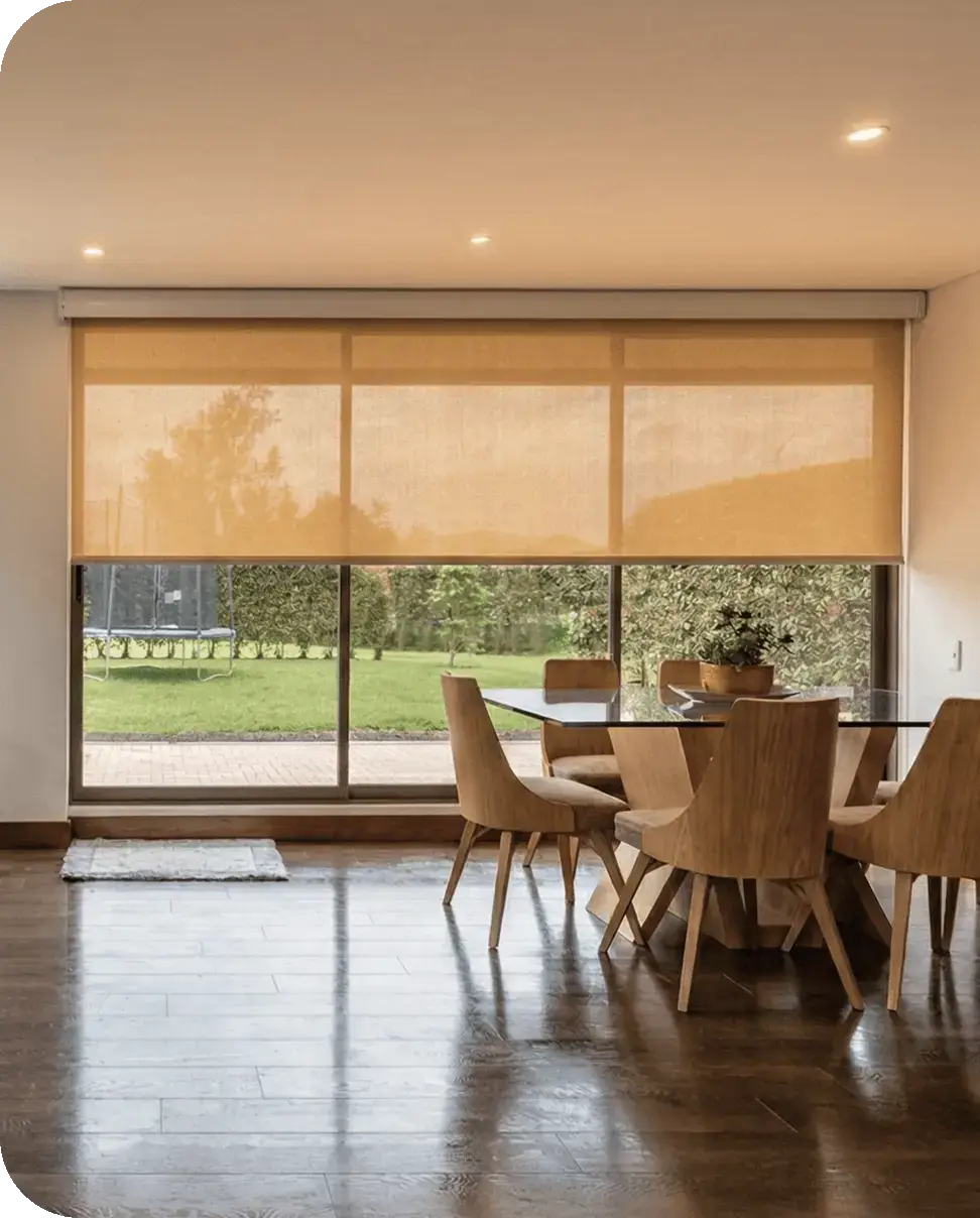 Wide light-filtering roller shade lowered over a dining-room glass door